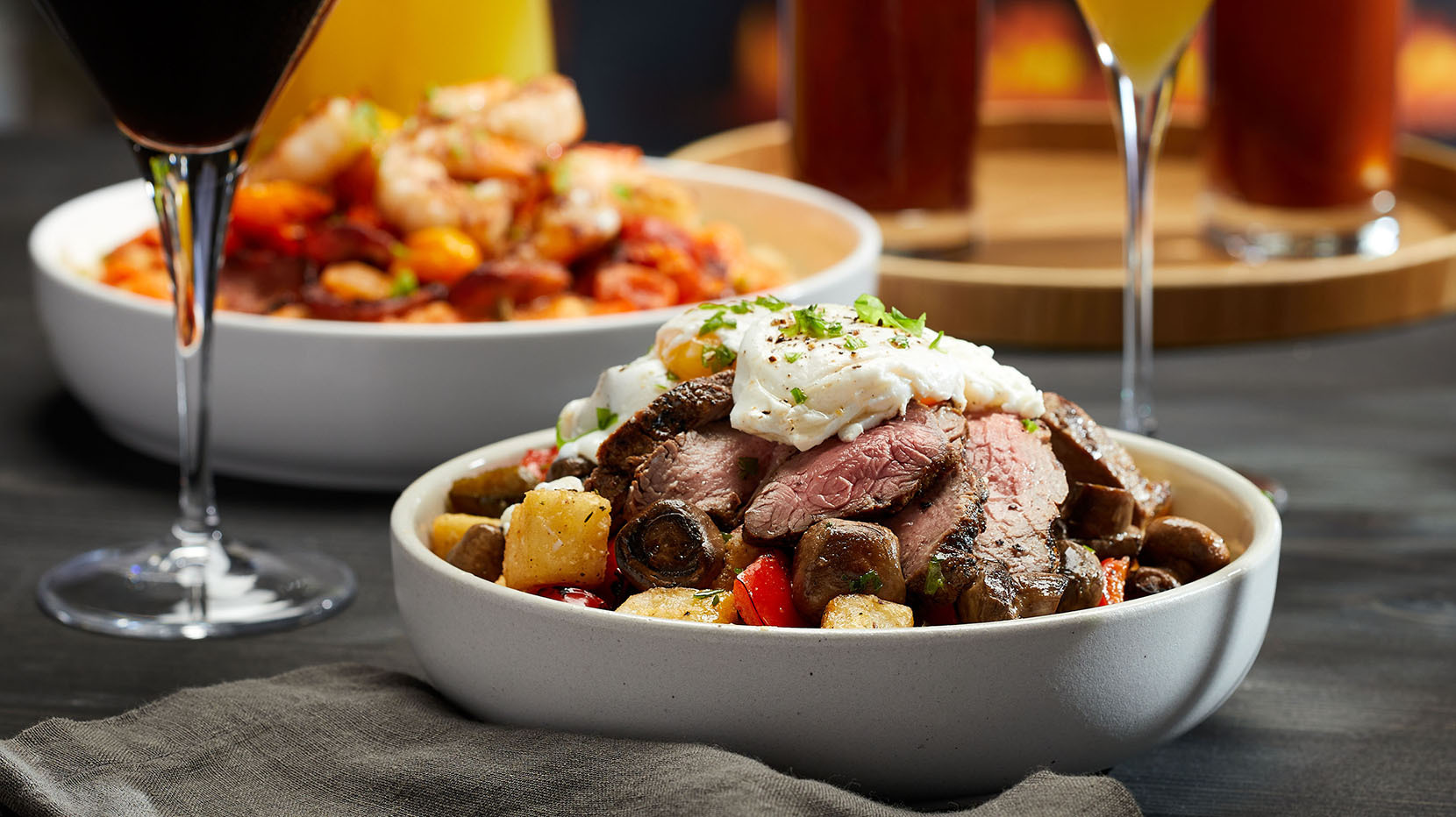 A dish featuring sirloin, potatoes and topped with an egg paired with a brunch cocktail.