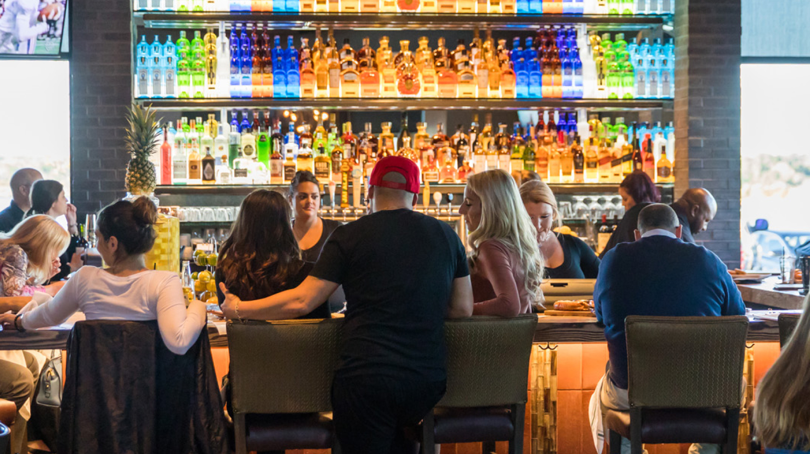 A group of people enjoying themselves at the bar area of Firebirds Wood Fired Grill restaurant.