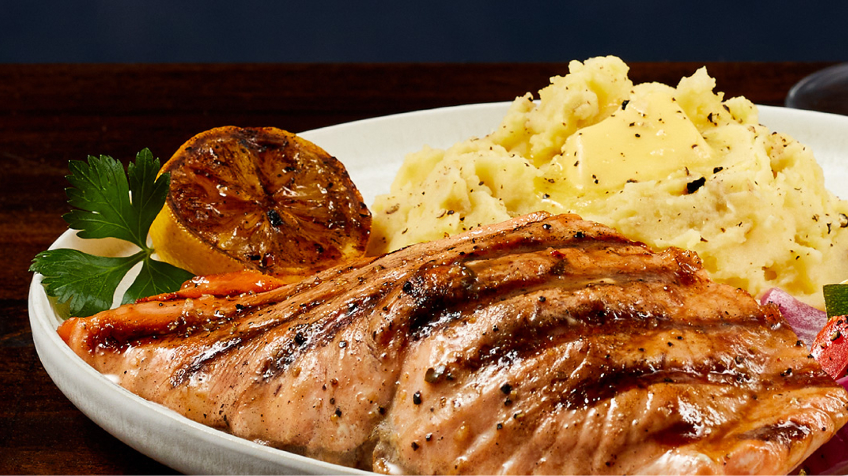 A plate of grilled salmon with potatoes.